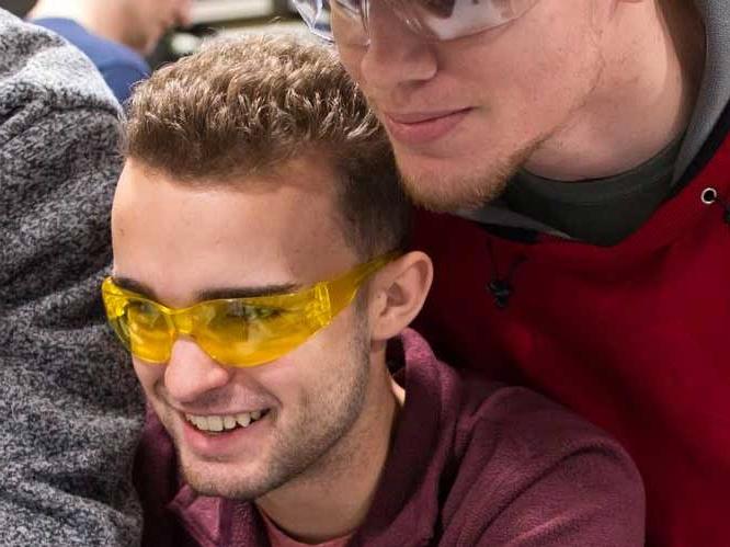 Two students wearing safety goggles focusing